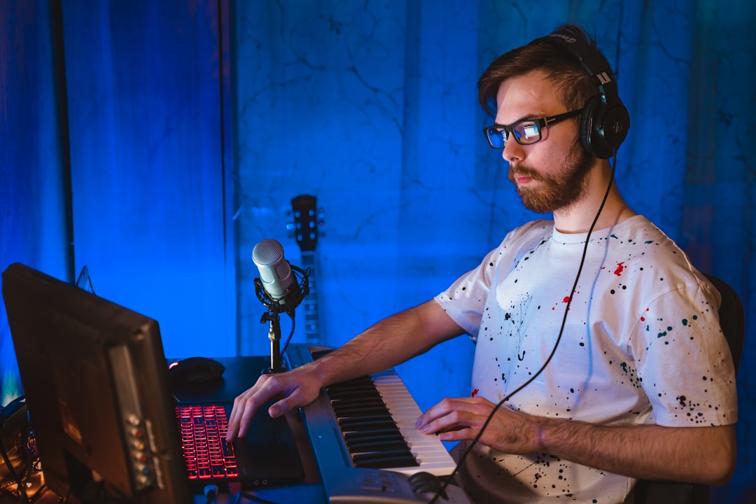 Man in blue and white polka dot button up shirt playing electric keyboard