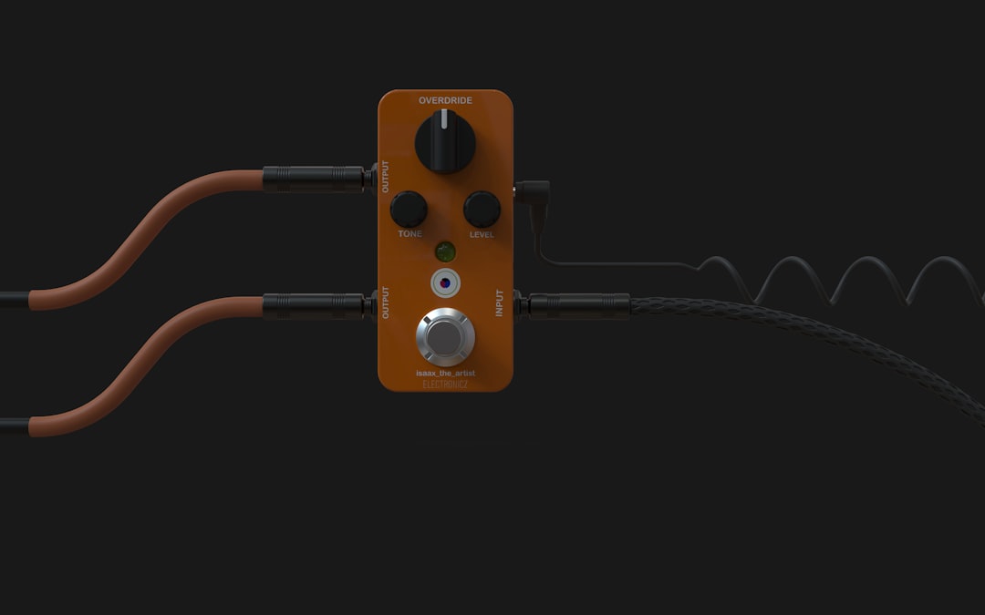Orange guitar pedal with cables on dark background