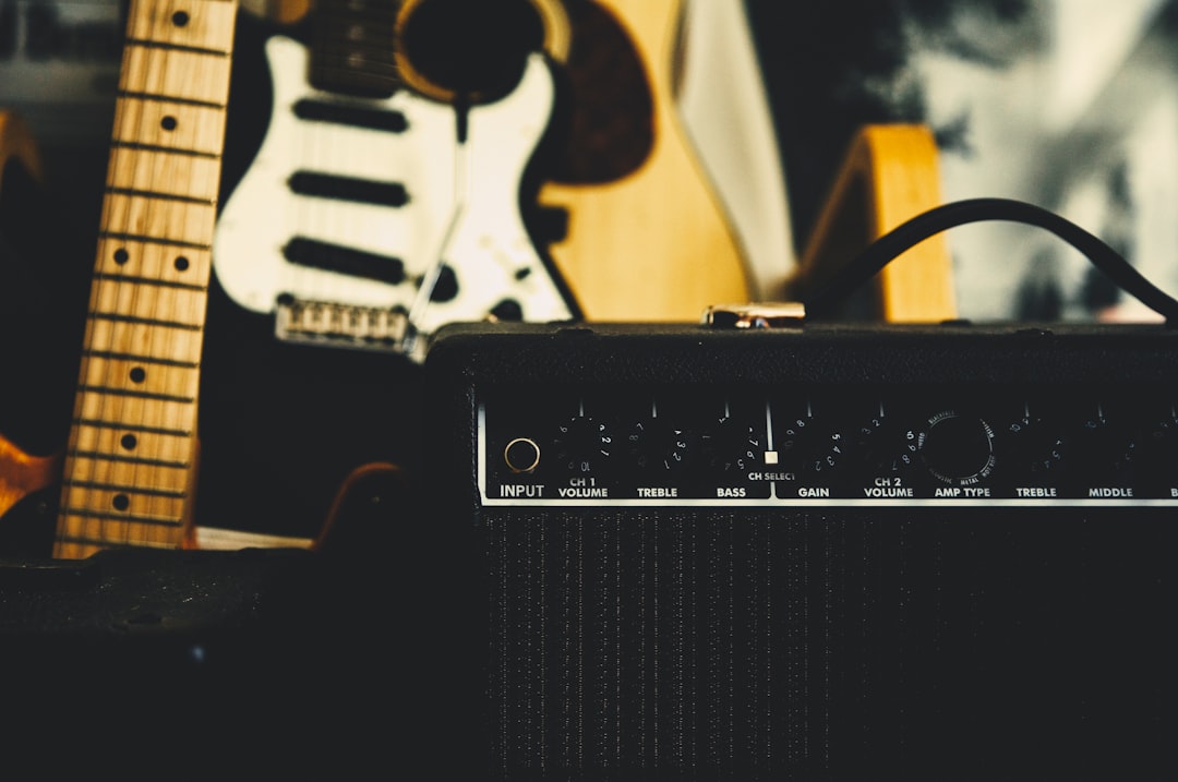 Black guitar amplifier beside electric guitar