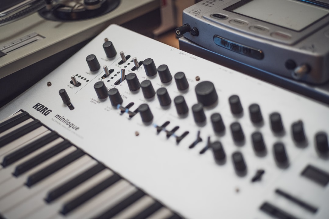 A white korg minilogue synthesizer with many knobs.