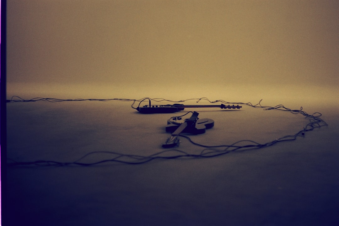 A guitar and amplifier lie on a sandy surface.