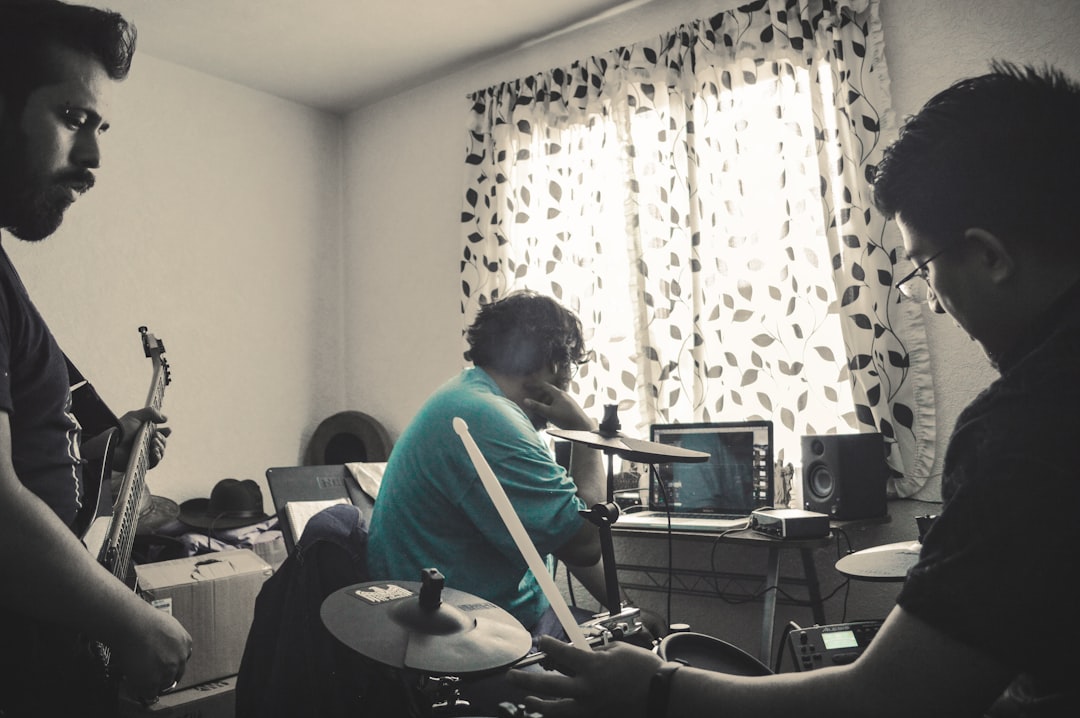 Musicians practicing in a room with a drum set.