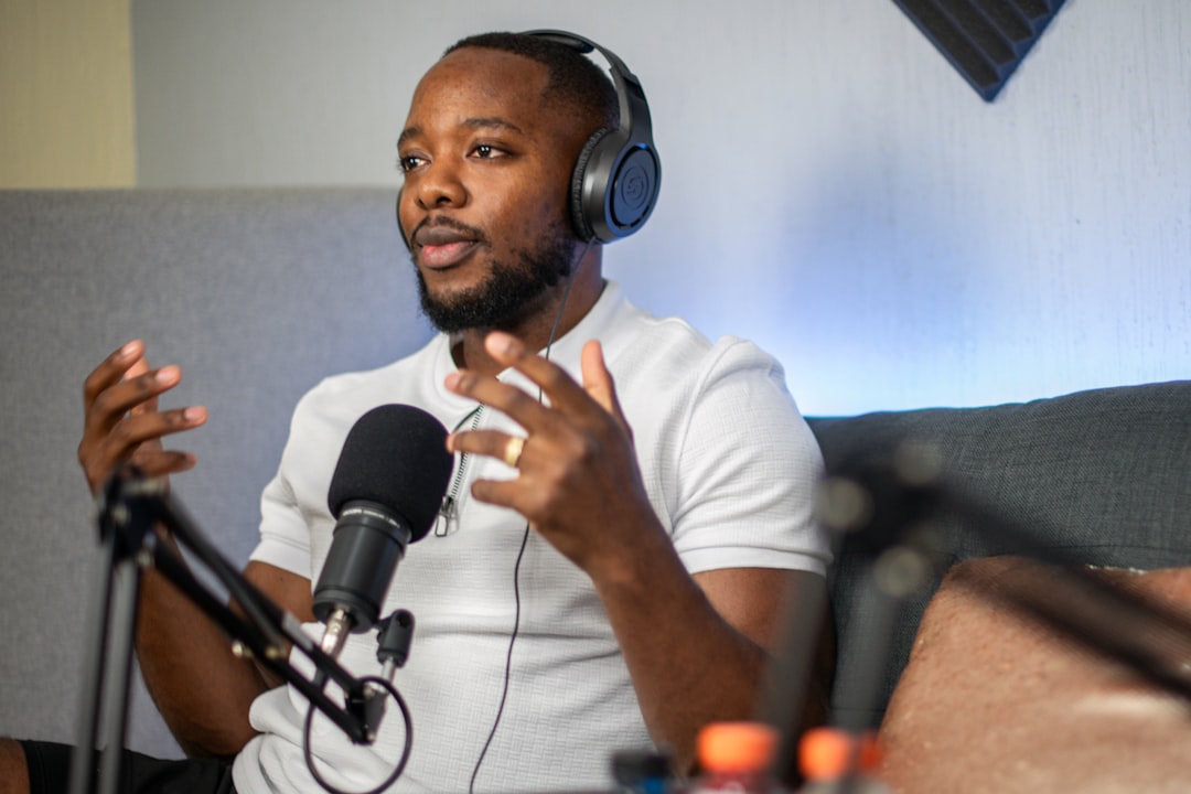 A man wearing headphones sitting in front of a microphone