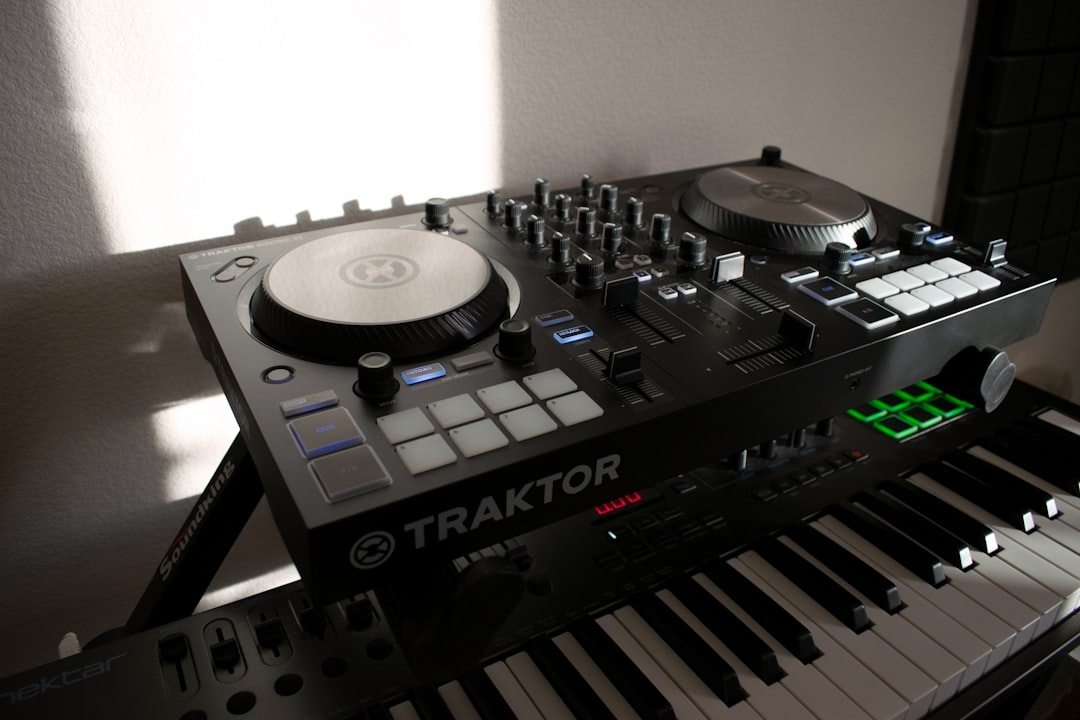 A black traktor dj controller sits on a musical keyboard.
