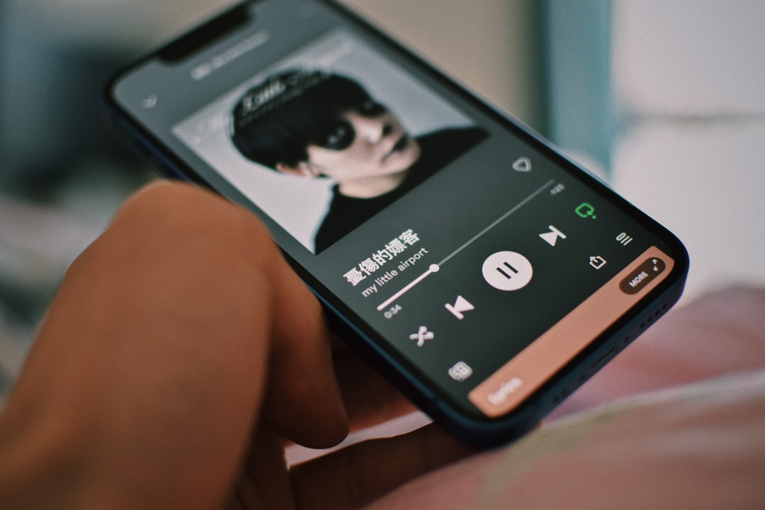 A person holding a cell phone with a music player on it