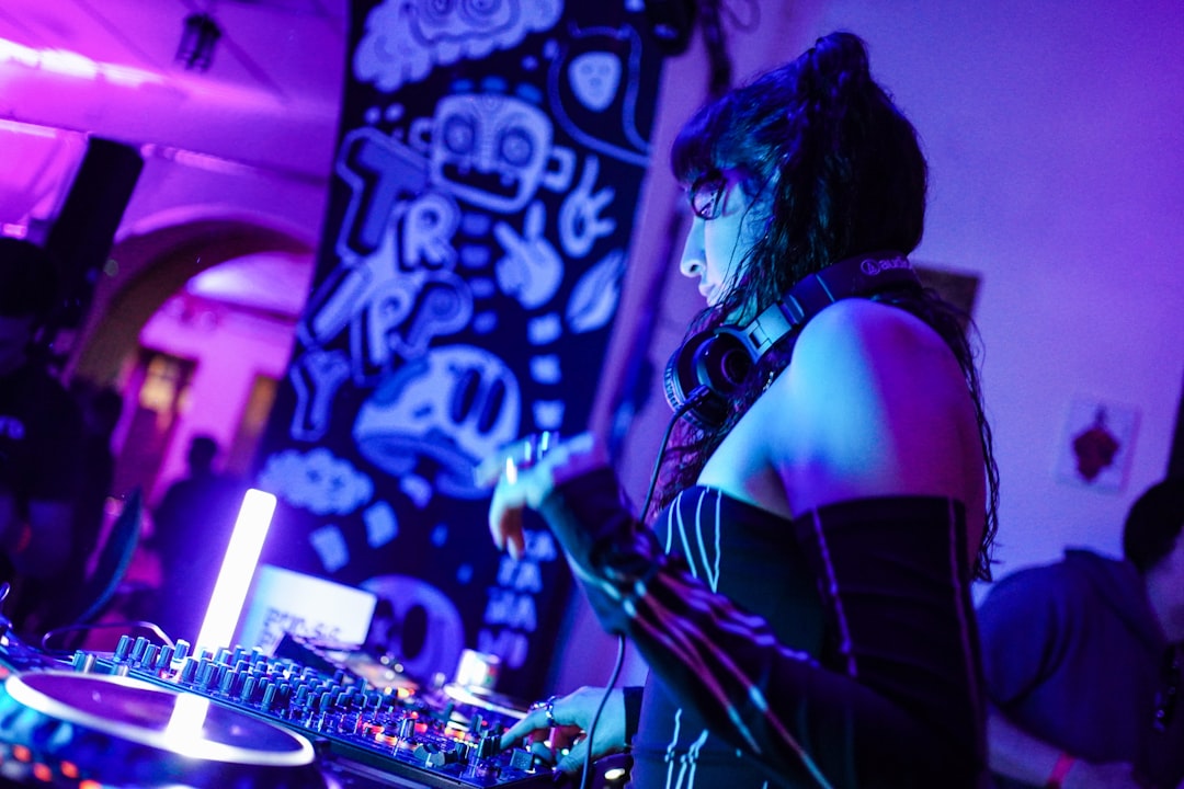 A woman dj plays music on turntables at a party.