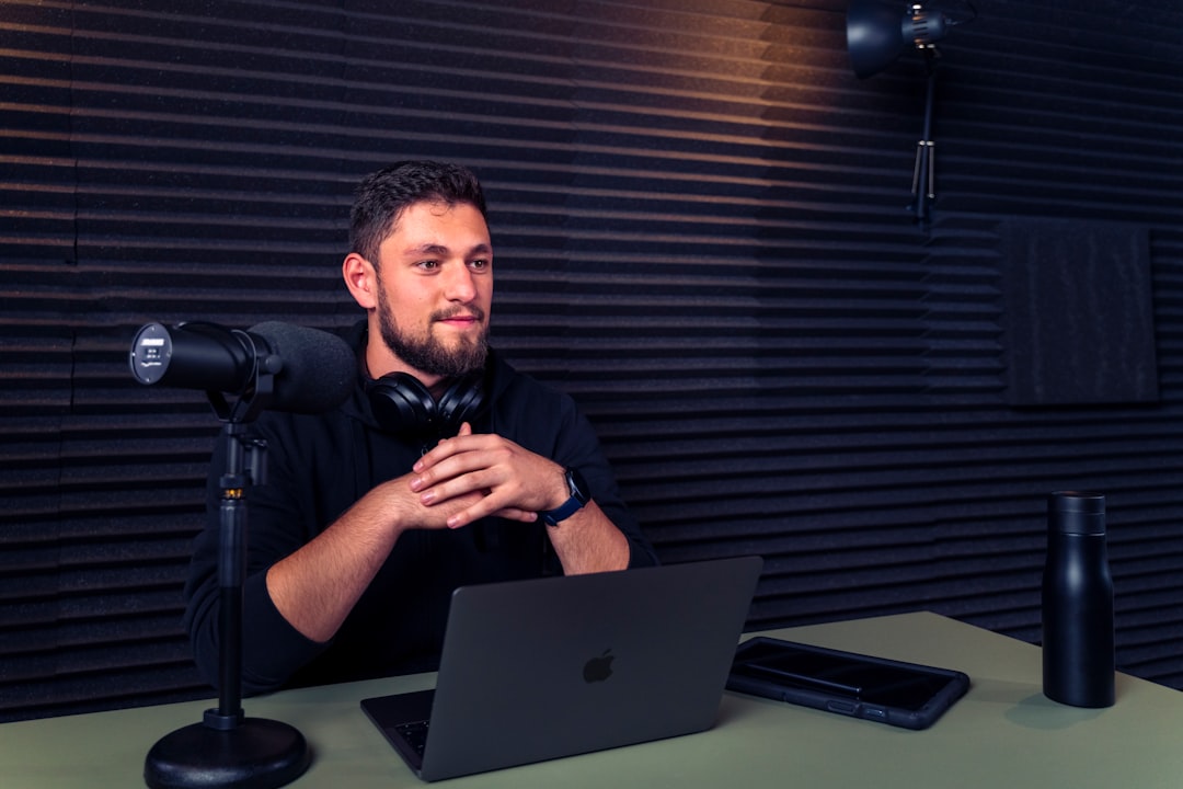 A man sitting at a desk with a laptop and microphone
