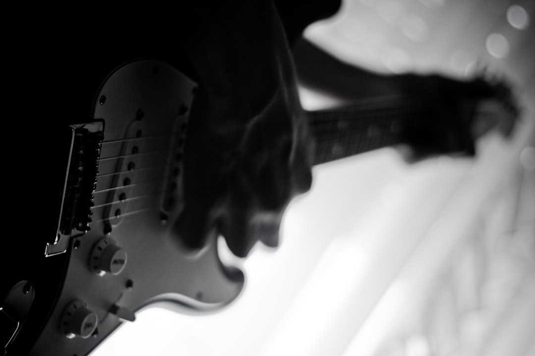 Grayscale photo of person playing electric guitar