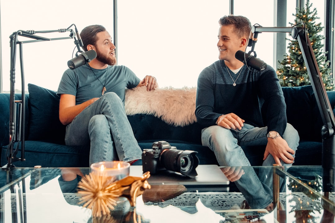 A couple of men sitting on a couch with a dog on a table