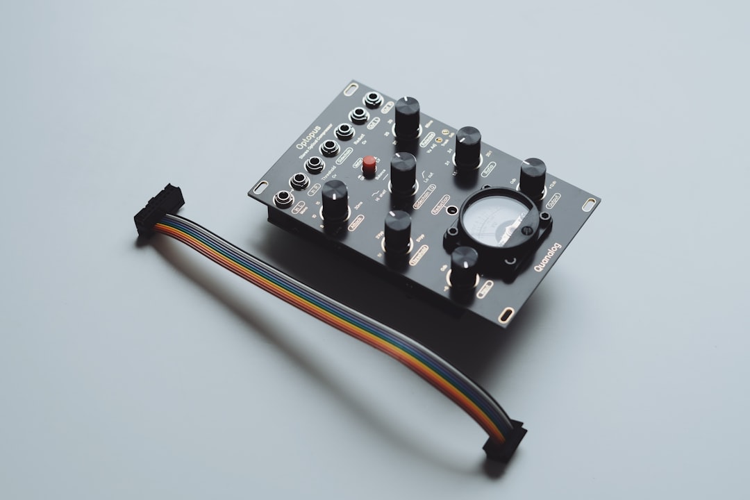A black electronic module with knobs and a cable