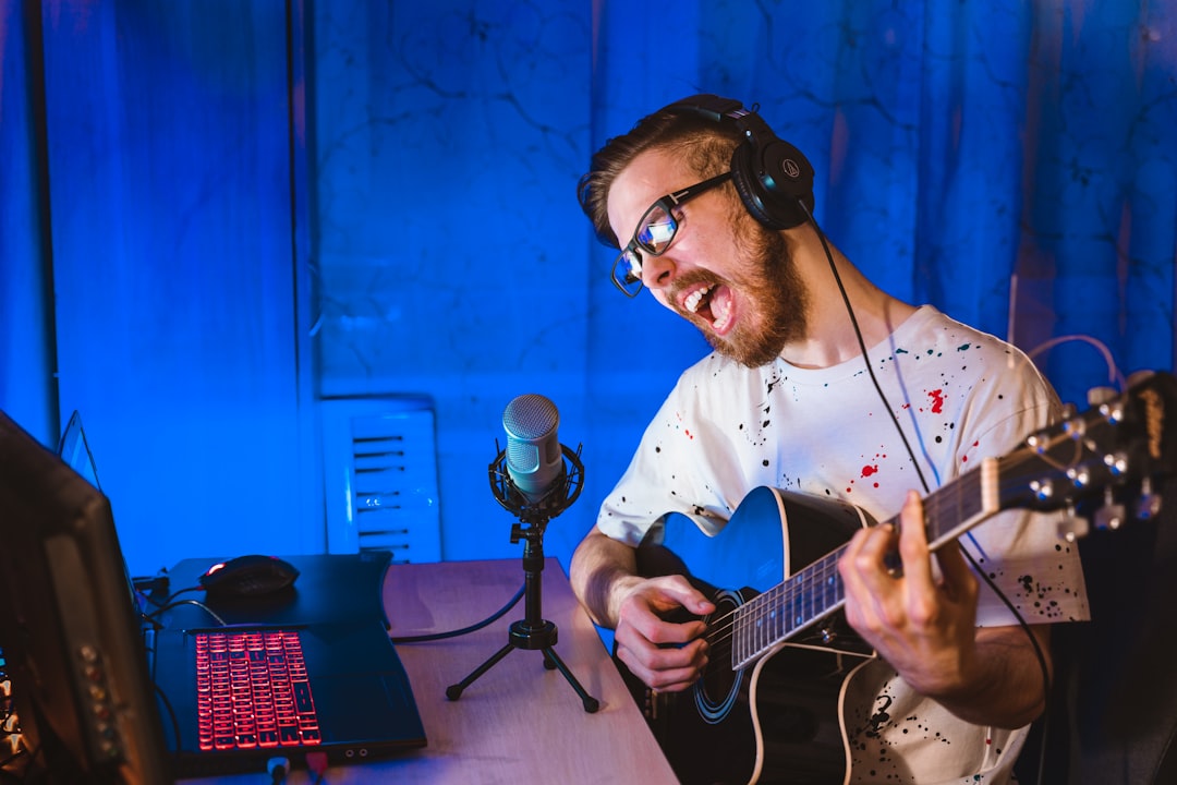 Man in white and black plaid dress shirt playing guitar